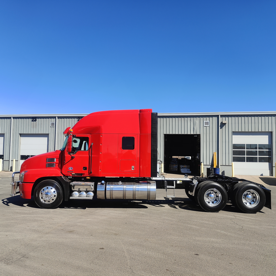 Red 2022 Mack AN64T70 sleeper cab tractor. Side view showing chrome fuel tanks, dual rear axles, and a black fifth wheel area.
