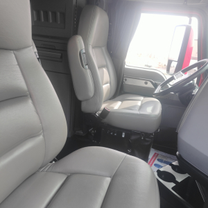 Truck cab interior showing gray cloth driver seat and passenger seat with steering wheel and dashboard visible.