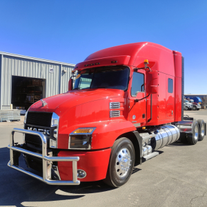 Red 2022 Mack AN64T70 conventional sleeper truck in a dealership lot, front three-quarter view, chrome bumper guard, dual rear axles, fuel tanks visible.