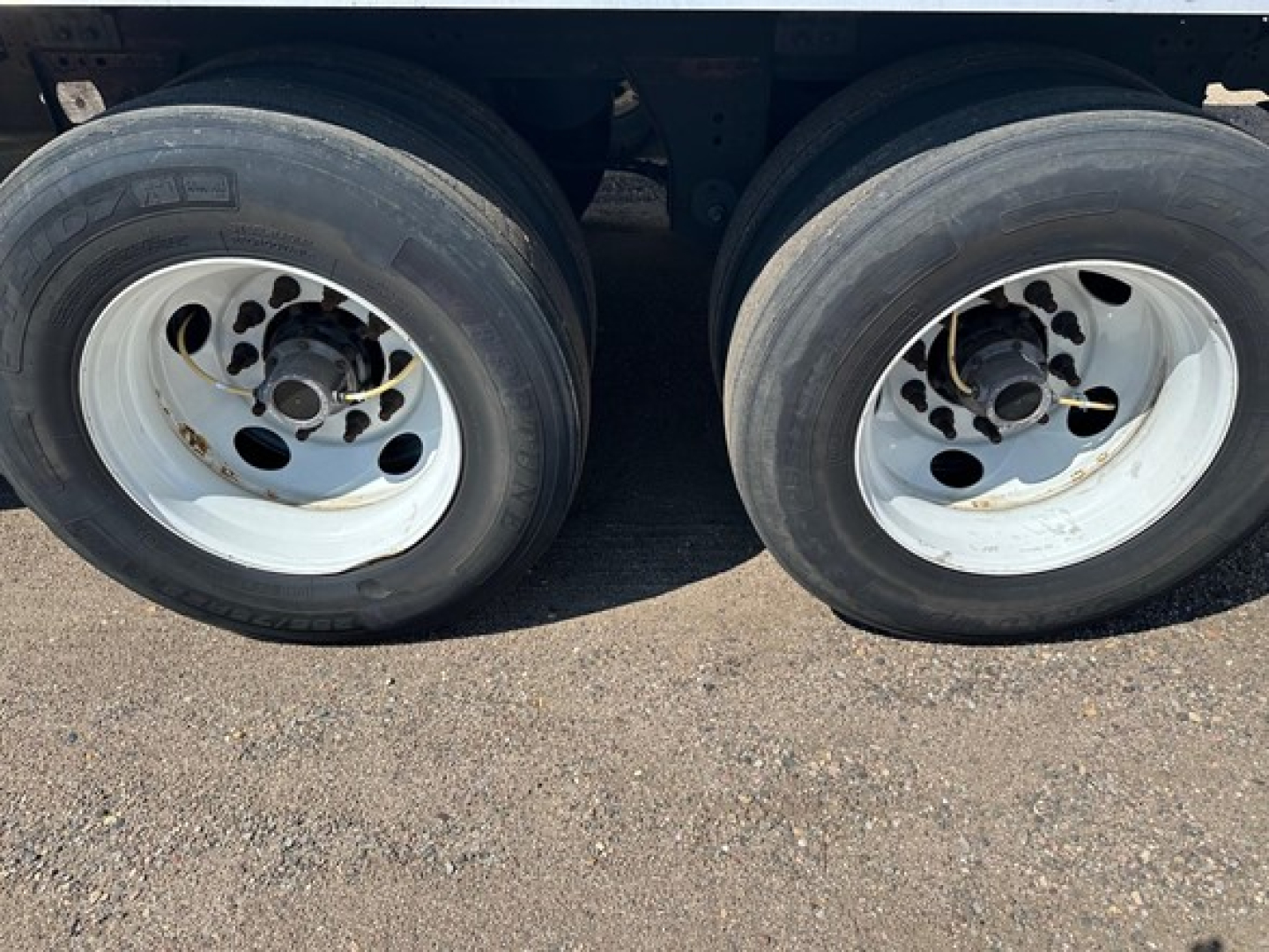 Dual trailer wheels and tires on a Great Dane Champion trailer show white rims and black tires undercarriage.