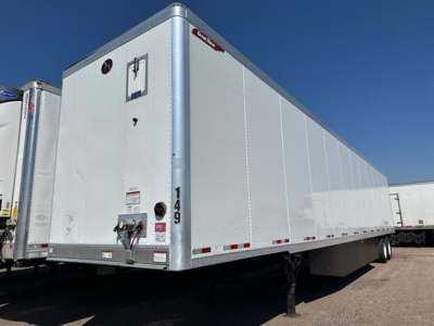 Great Dane Champion trailer in a yard showing side panel, rear doors, and landing gear. Visible text includes model number 149 and a small red/white label on the front corner panel.