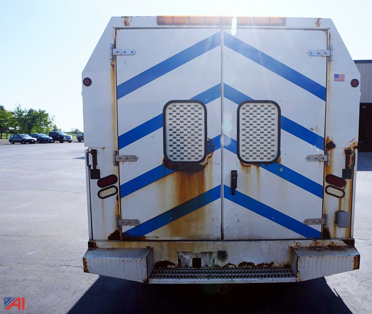 Rear view of a used 2013 Ford E350 utility/service truck with double rear doors, blue chevron decals, rust stains, and utility bumper.