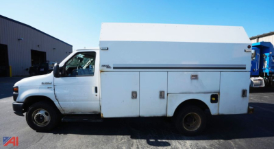 Ford E-350 utility service truck in profile showing large white utility box with compartments along side and cab in foreground.