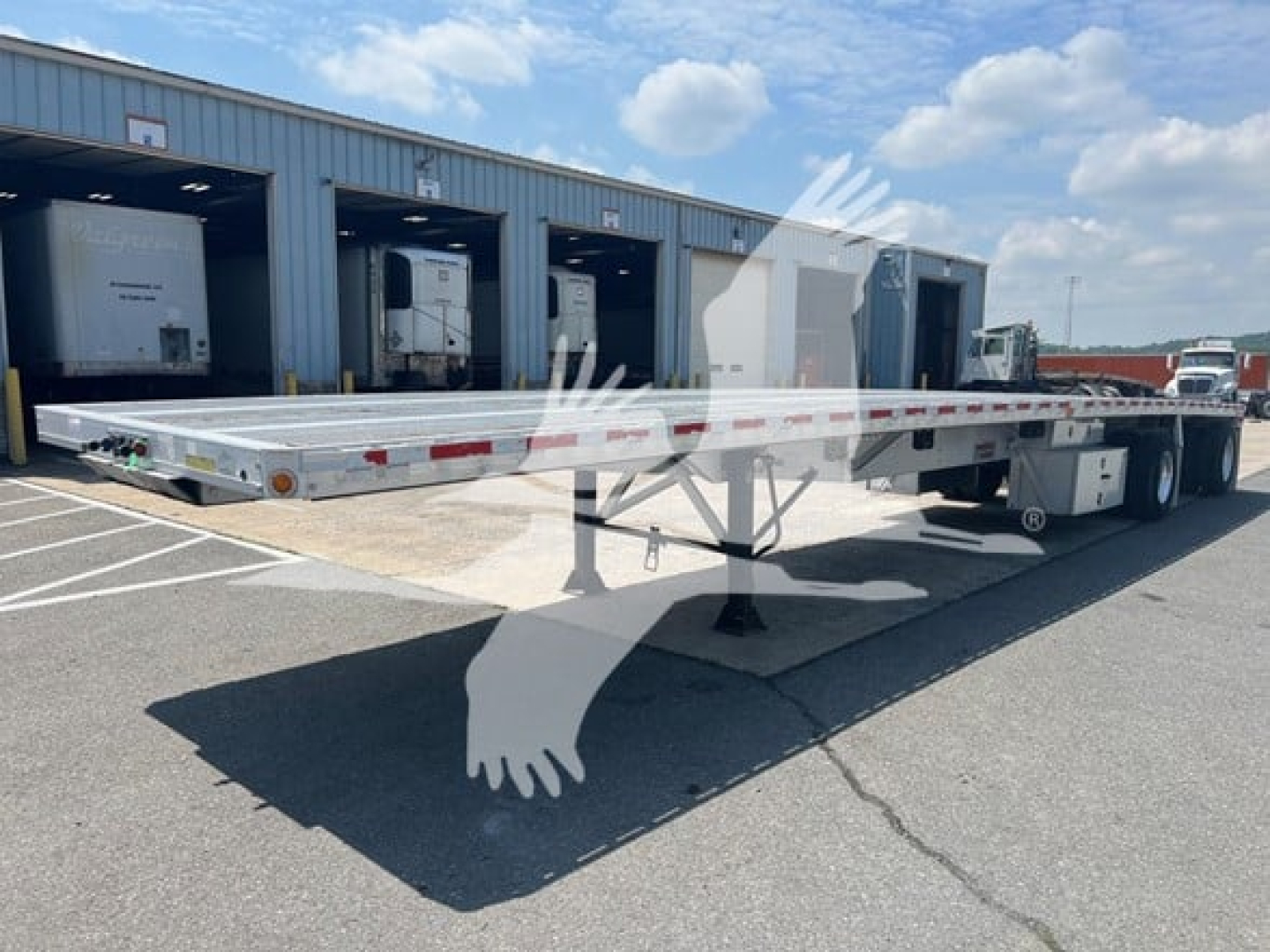 Flatbed trailer in service showing long aluminum deck and tandem axles, no visible branding text.
