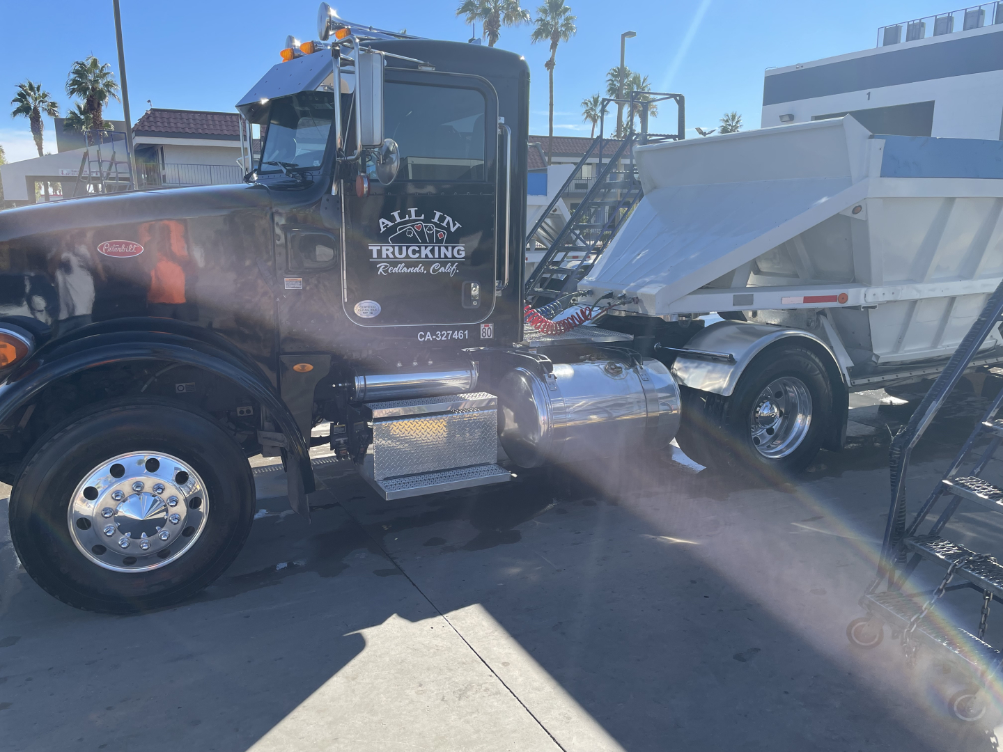 Conventional day cab 2014 Peterbilt 376 truck with black paint, chrome fuel tanks and dump trailer attached, branding on door reading All In Trucking, CA-#_NUMBER visible.