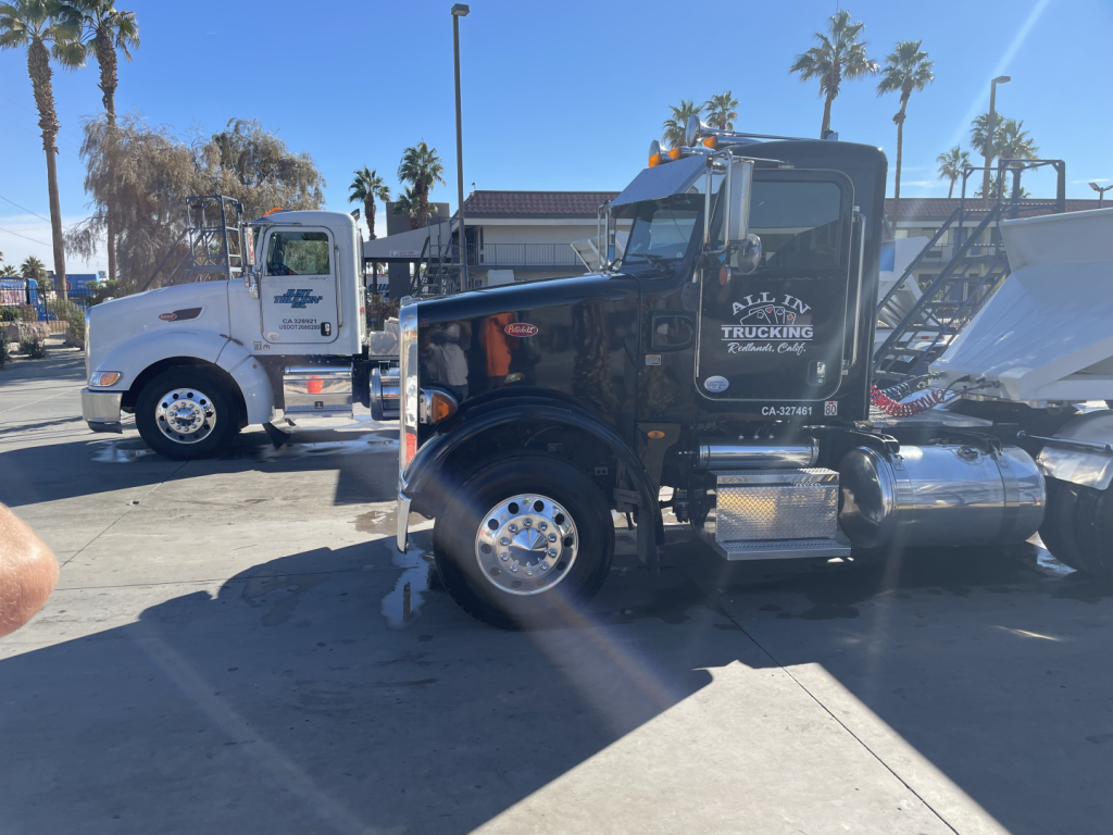 Peterbilt 376 conventional daycab truck side view showing All In Trucking logo on door and chrome fuel tanks
