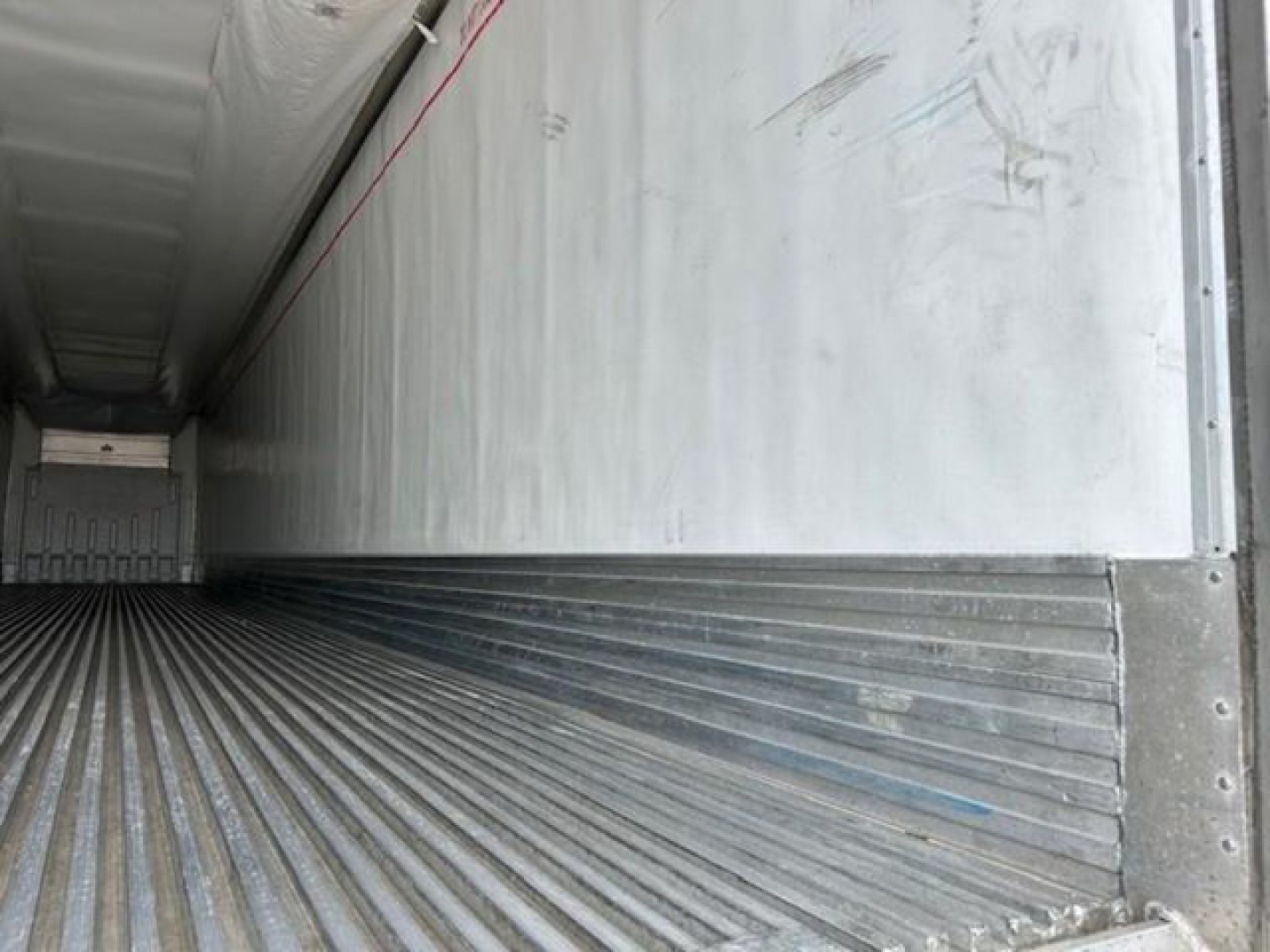 Trailer interior showing corrugated metal floor and side walls of a refrigerated trailer