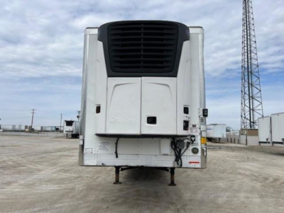 Refrigerated trailer front view showing cargo refrigeration unit and landing legs at a truck yard.