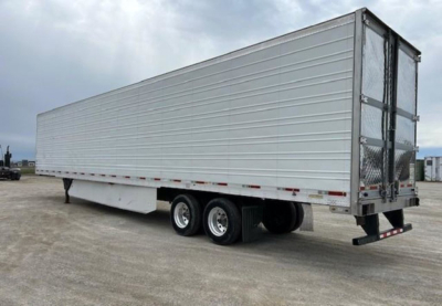 Utility reefer trailer in side view showing tandem axles and rear doors, silver aluminum exterior, no visible branding.