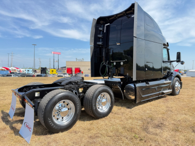Peterbilt 579 tractor in profile with empty sleeper cab, black exterior, rear dual axles, chrome wheels, viewed from left rear. VIN tag and stock info not visible on image.