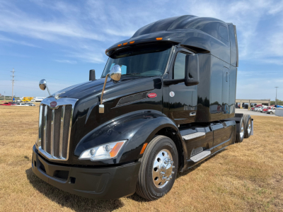 Peterbilt 579 conventional sleeper truck in black, front-left view, chrome bumper and grille, visible side mirrors, daytime sky.