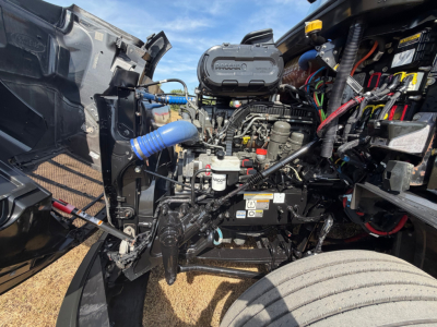 Peterbilt 579 engine bay showing air intake, hoses, wiring, and engine components with visible labels and caps.
