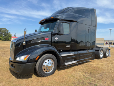 Peterbilt 579 tractor unit in black, side view showing sleeper cab, front grille, chrome wheels, and fuel tanks.