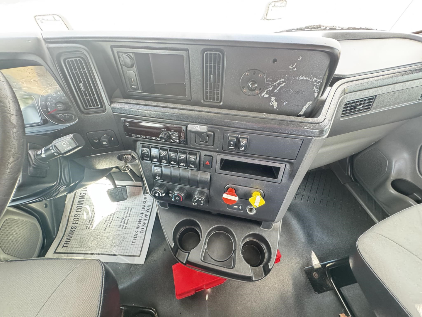 Interior cab of 2018 International LT truck showing dashboard controls, ignition with key, cup holders, storage compartments, and switches.