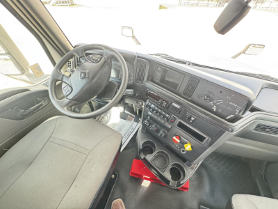 Interior of 2018 International LT daycab showing steering wheel, dashboard controls, center console with cupholders and storage, gear lever, and driver's seat.