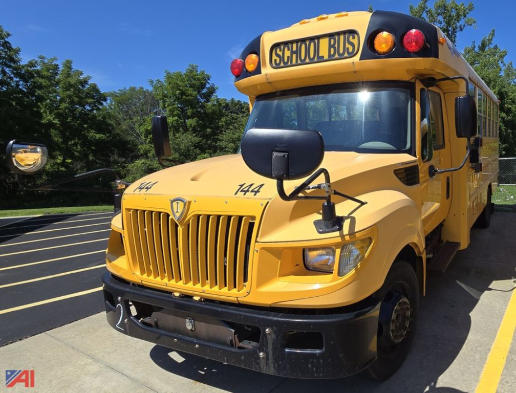 Yellow IC Corporation International school bus with wheelchair lift, front grille, headlights, and 'SCHOO L BUS' sign on top; parking lot in background.