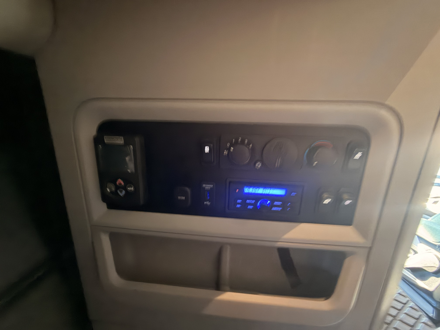 Kenworth T680 cab interior dashboard panel with controls and blue-lit radio/display visible.