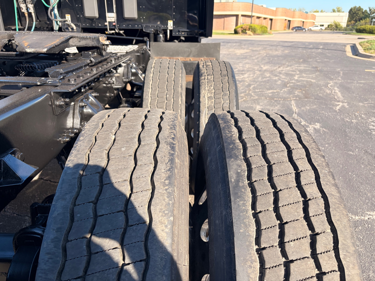 Kenworth T680 tractor rear view showing dual rear axles and tires with tread grooves, side chassis components and undercarriage.