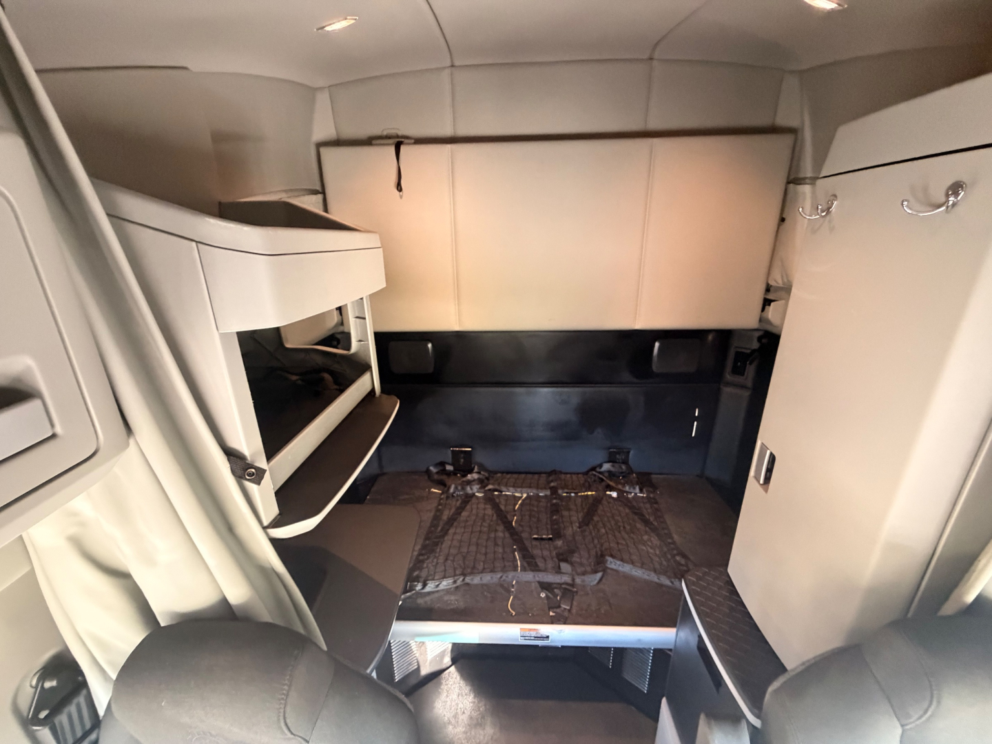Interior of a Kenworth T680 sleeper cab showing bunk structure and cabinetry, with a floor plate and step visible.