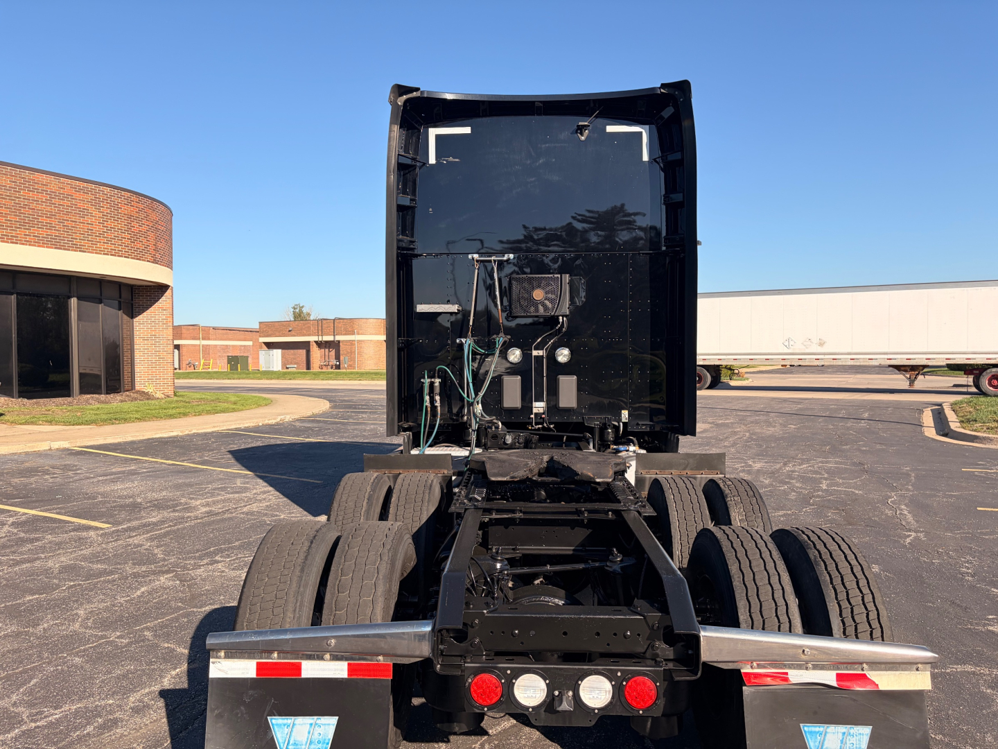 Kenworth T680 tractor rear view showing fifth wheel mount, dual rear axles, and back of cab with sleeper.