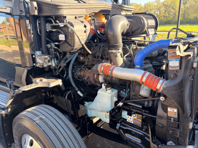Kenworth T680 engine bay showing turbocharger, intake piping, coolant reservoir, and various hoses and cables.
