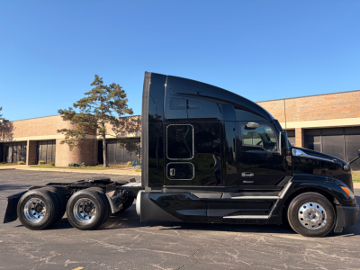Kenworth T680 tractor cab side view showing black exterior and sleeper cab with chrome wheels and dual rear axles.