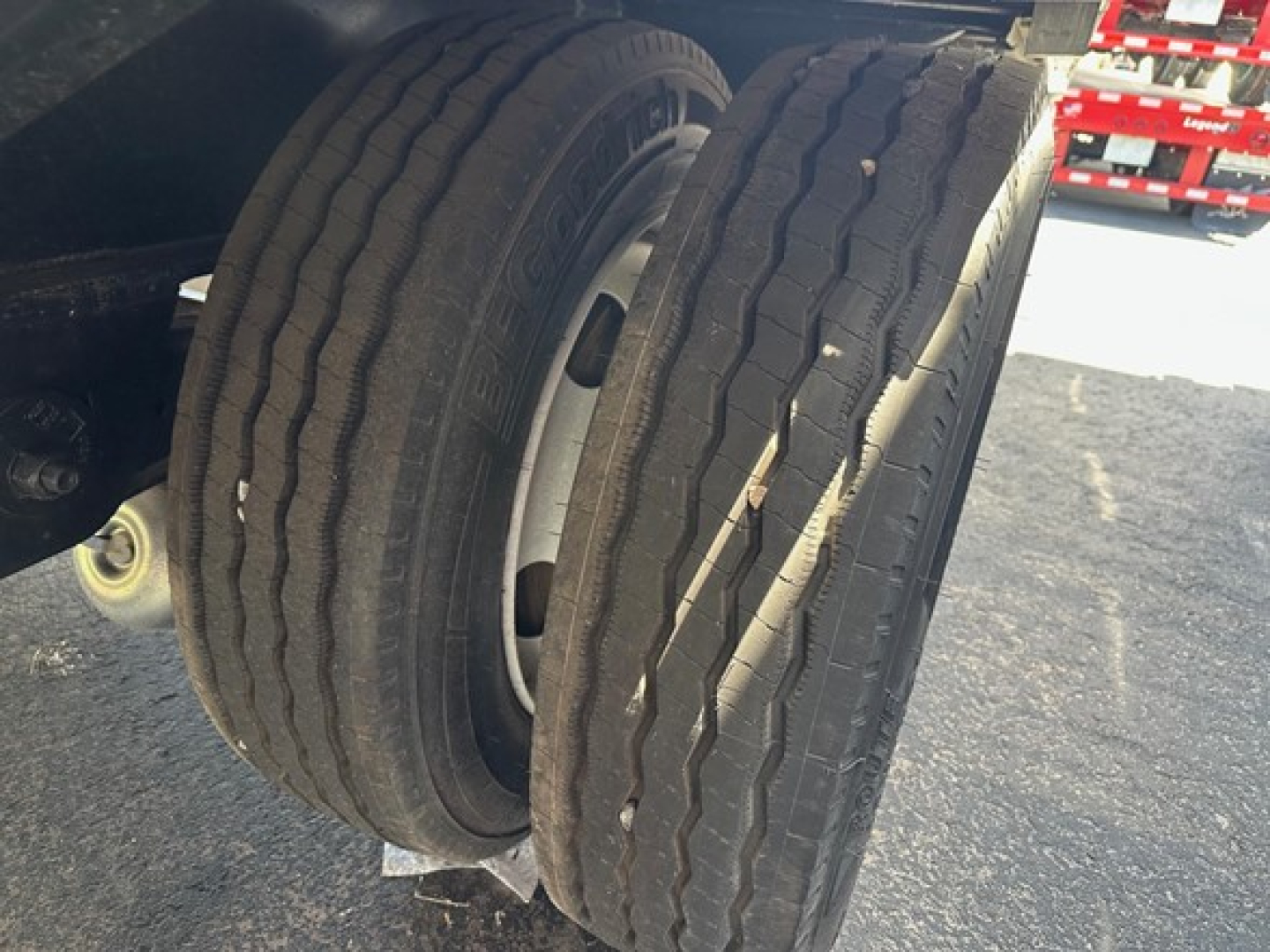 Dual rear trailer tires on a drop deck trailer with visible treads and rims.
