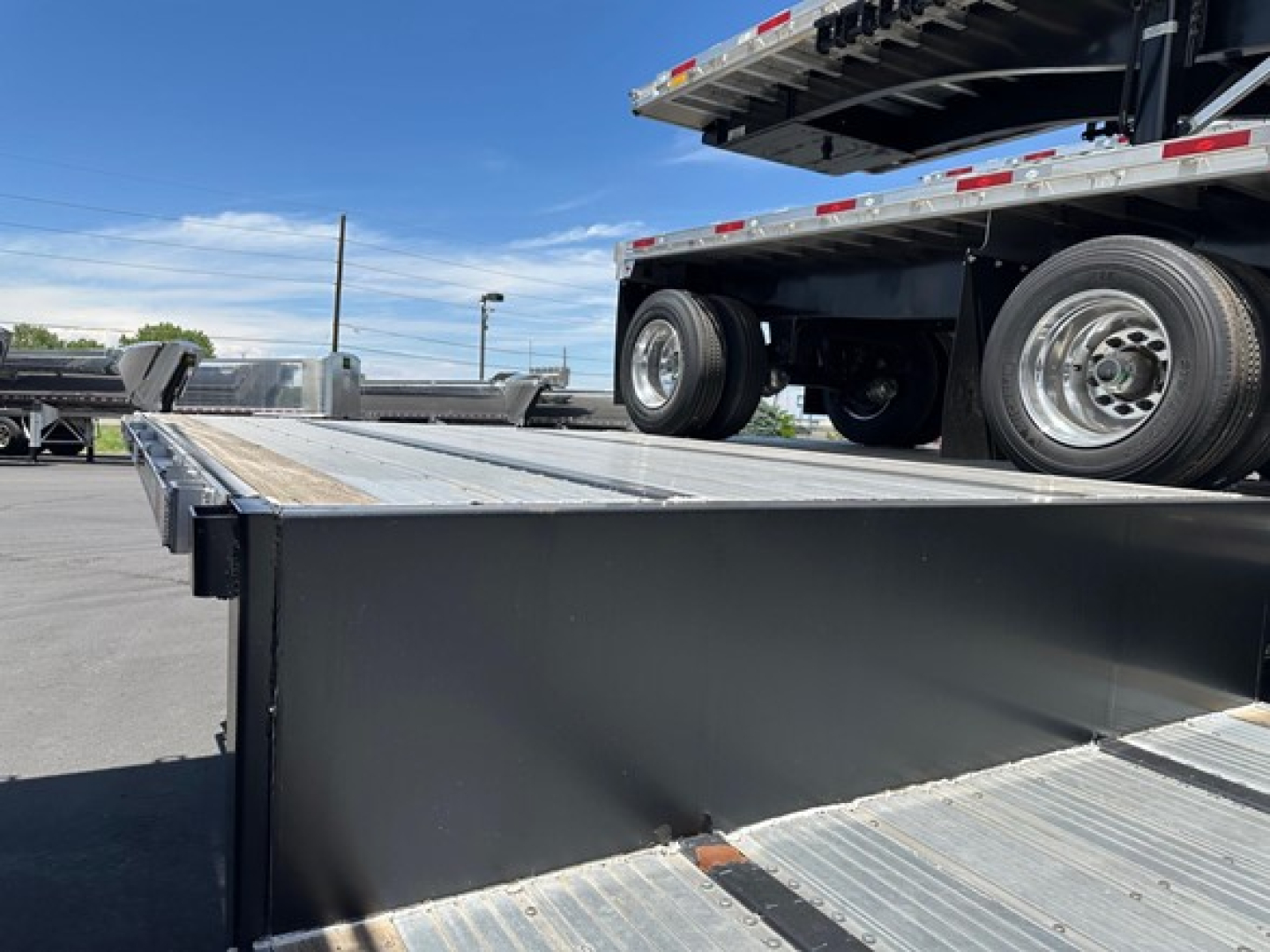 Utility trailer deck showing combo drop deck with wheels on upper level and metal plank surface.