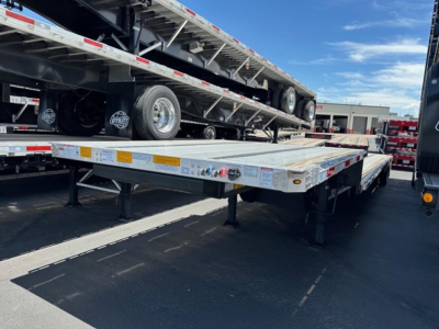 Utility 4000Ae combo drop deck trailer with flatbed sections and dual tandem wheels on a parked trailer, side decals and safety markings visible.