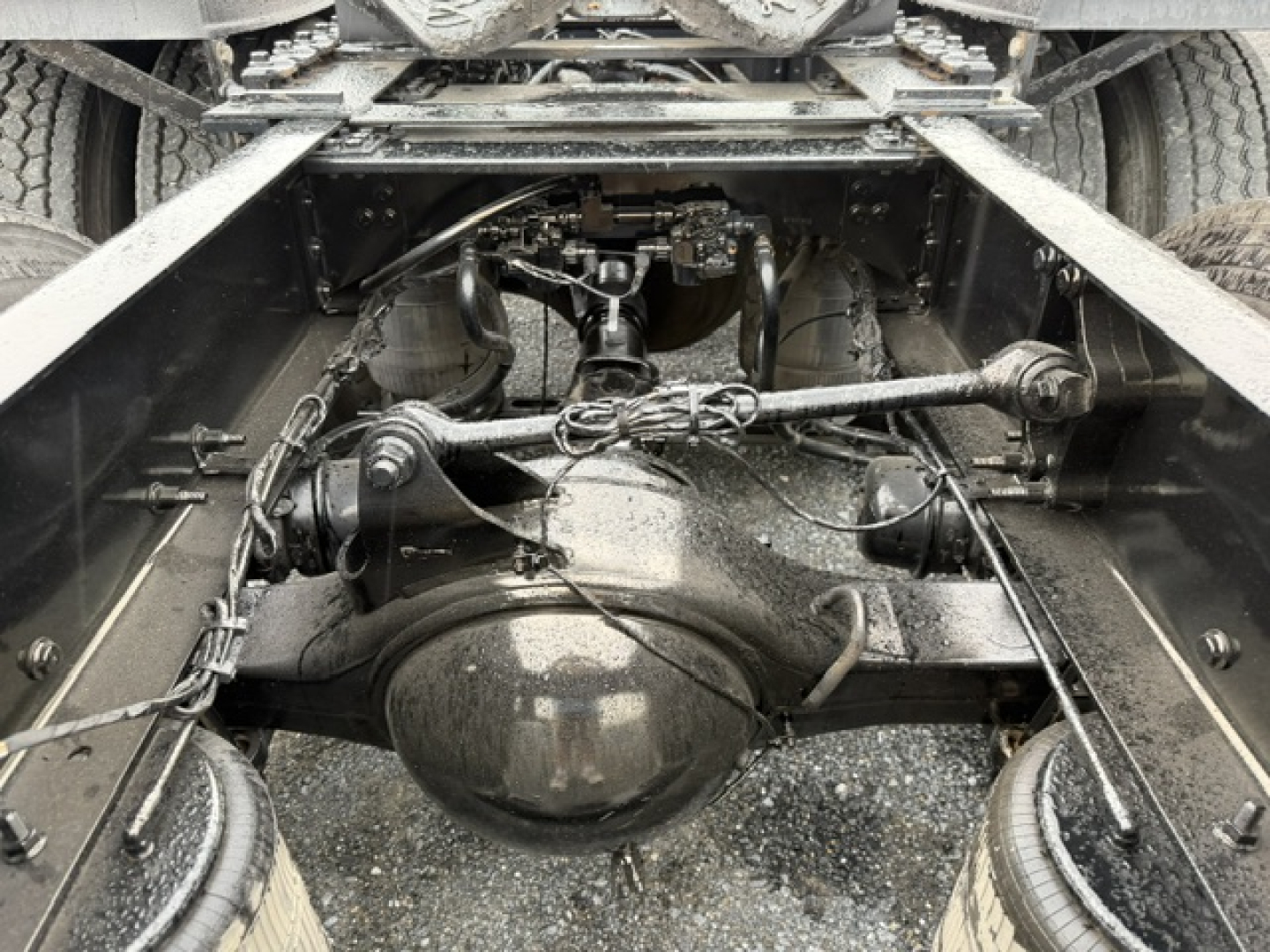 Volvo VNL64T300 chassis view showing rear axle differential and driveline components under the cab with suspension arms and leaf springs.
