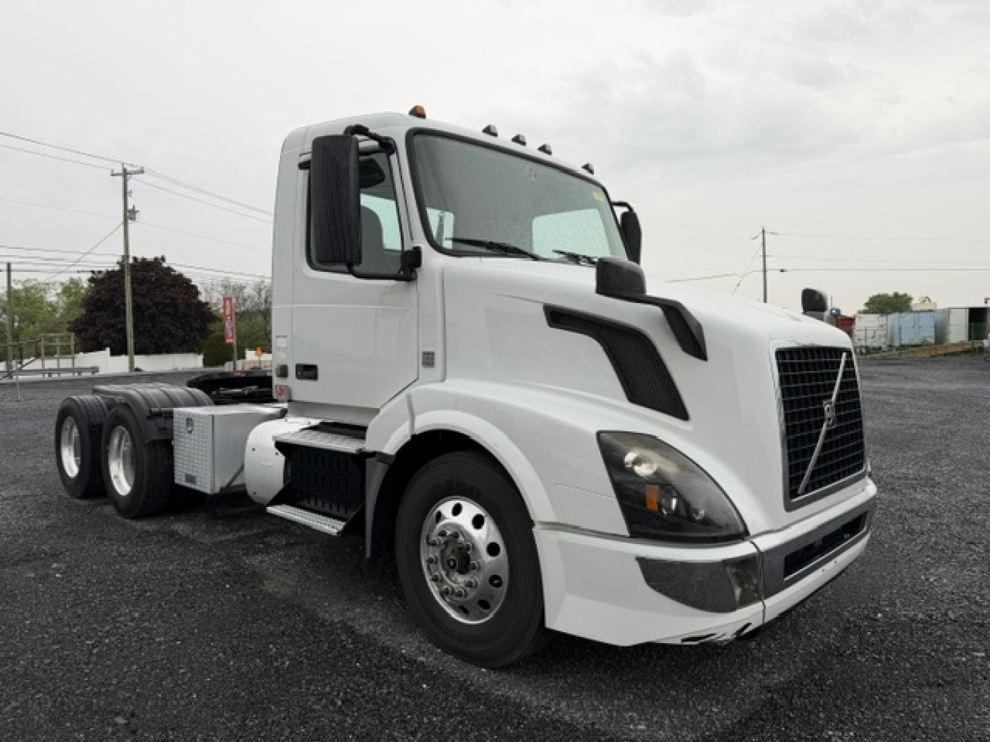 Volvo VNL64T300 conventional daycab tractor in white, front-left view showing cab with large grille, side mirrors, and dual rear axles.