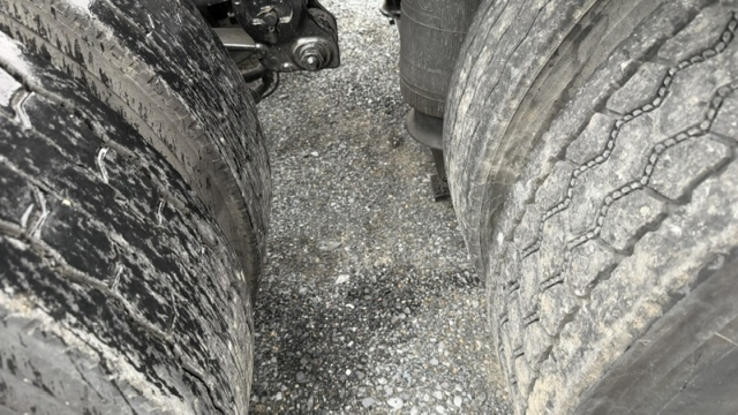 Volvo VNL64T300 engine bay/underbody showing tires and suspension components with road grime on dual rear axles.