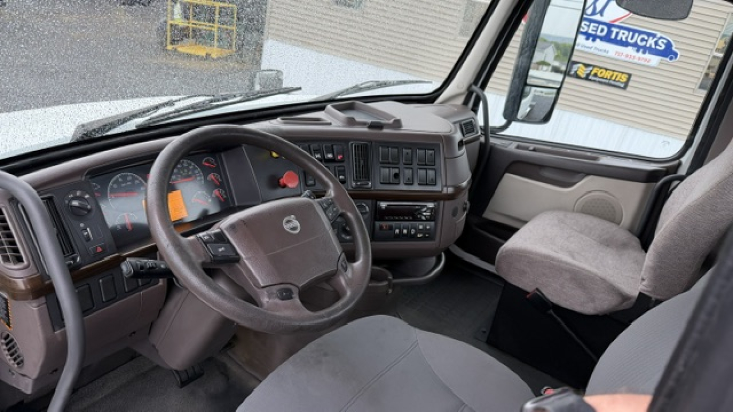 Volvo truck cab interior showing steering wheel, dashboard, and front seats. Visible labels include Volvo emblem on steering wheel and instrument cluster markings.