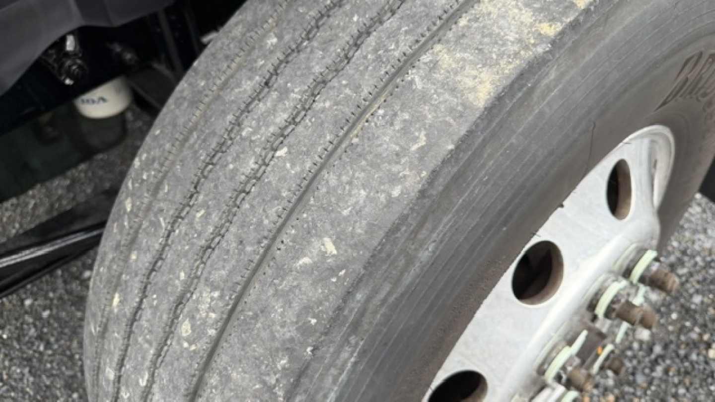 Truck wheel and tire along with part of the Volvo VNL64T300 undercarriage showing tire tread and wheel hub.
