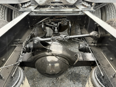 Volvo VNL64T300 chassis view showing rear axle differential and driveline components under the cab with suspension arms and leaf springs.
