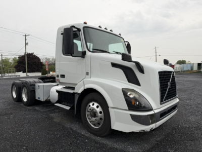 Volvo VNL64T300 conventional daycab tractor in white, front-left view showing cab with large grille, side mirrors, and dual rear axles.