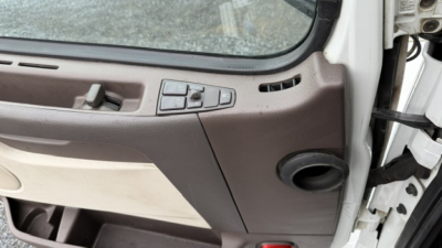 Interior of Volvo VNL truck cabin with door panel and control switches visible.
