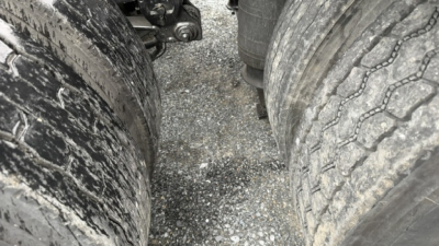 Volvo VNL64T300 engine bay/underbody showing tires and suspension components with road grime on dual rear axles.