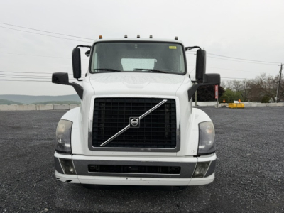 Volvo VNL64T300 conventional daycab truck front view with large black grille, Volvo emblem, white cab, rectangular headlights, and front bumper.