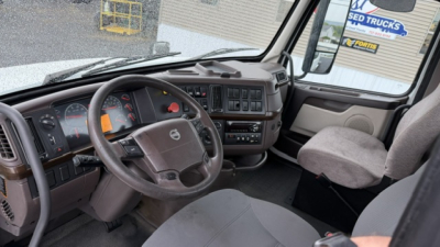 Volvo truck cab interior showing steering wheel, dashboard, and front seats. Visible labels include Volvo emblem on steering wheel and instrument cluster markings.