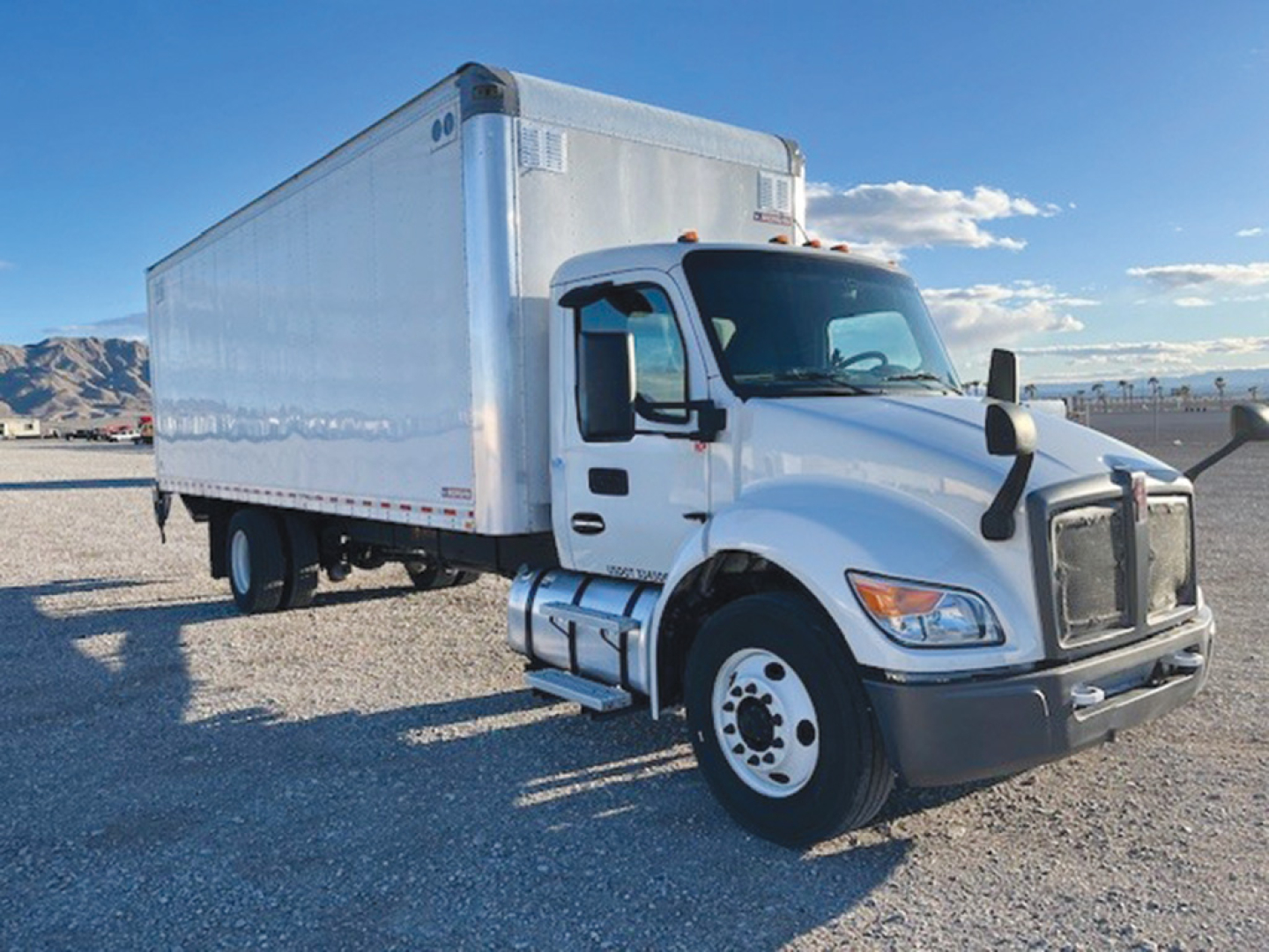 Kenworth T-270 box truck in a gravel lot showing side cab and cargo box with white exterior.