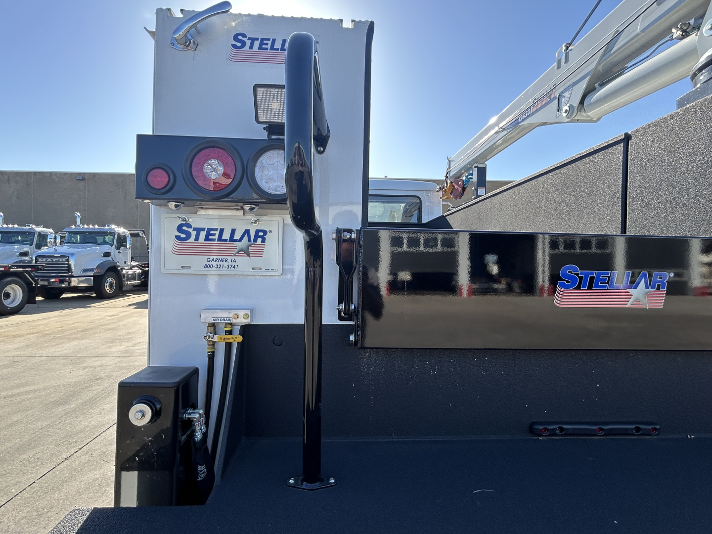 Truck bed view of a 2025 Mack MD7 service truck with Stellar crane equipment, Stella branding, and hydraulic hoses visible near the rear.
