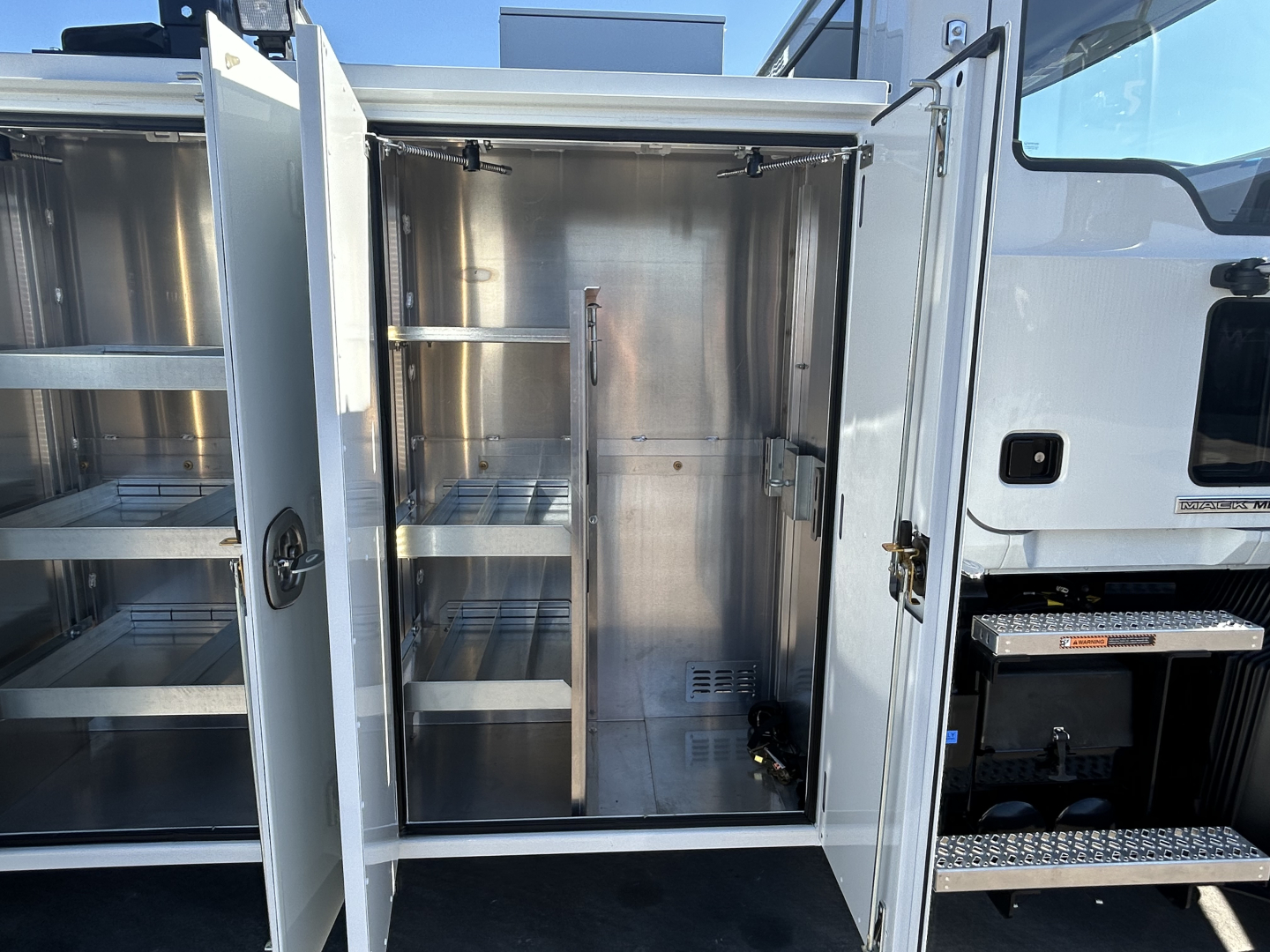 MD7 service body with open rear compartments showing metal shelving and storage cabinets.