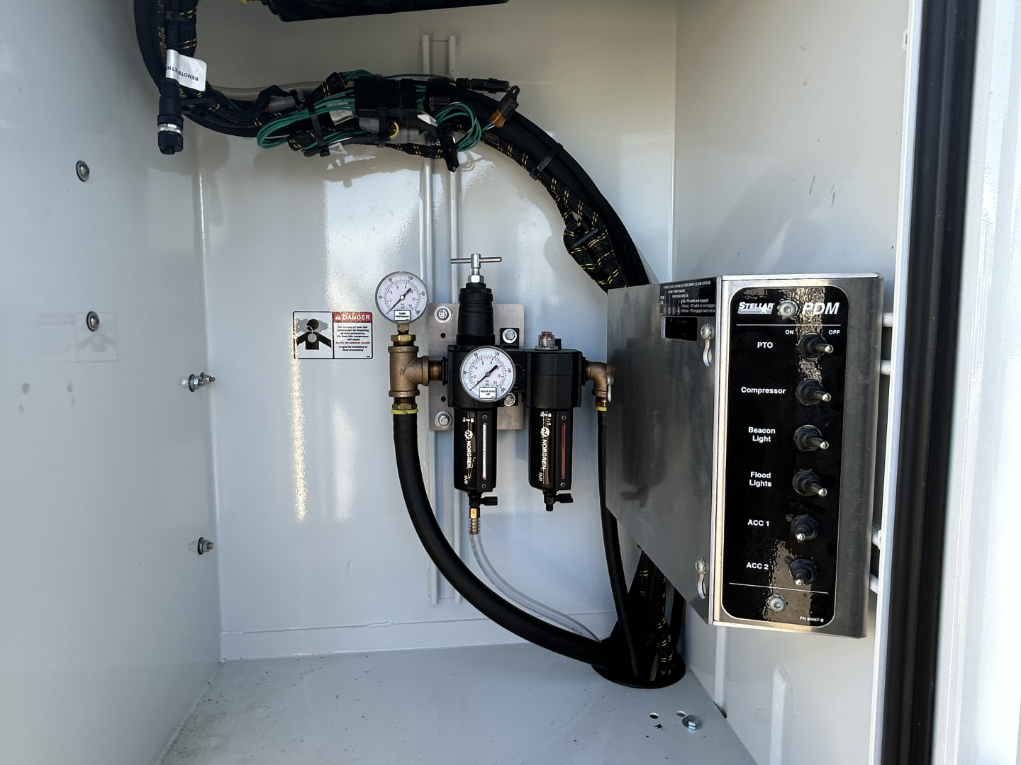 Mack MD7 service truck interior with hydraulic manifold and gauges showing label text, control panel, hoses, and pressure gauges.