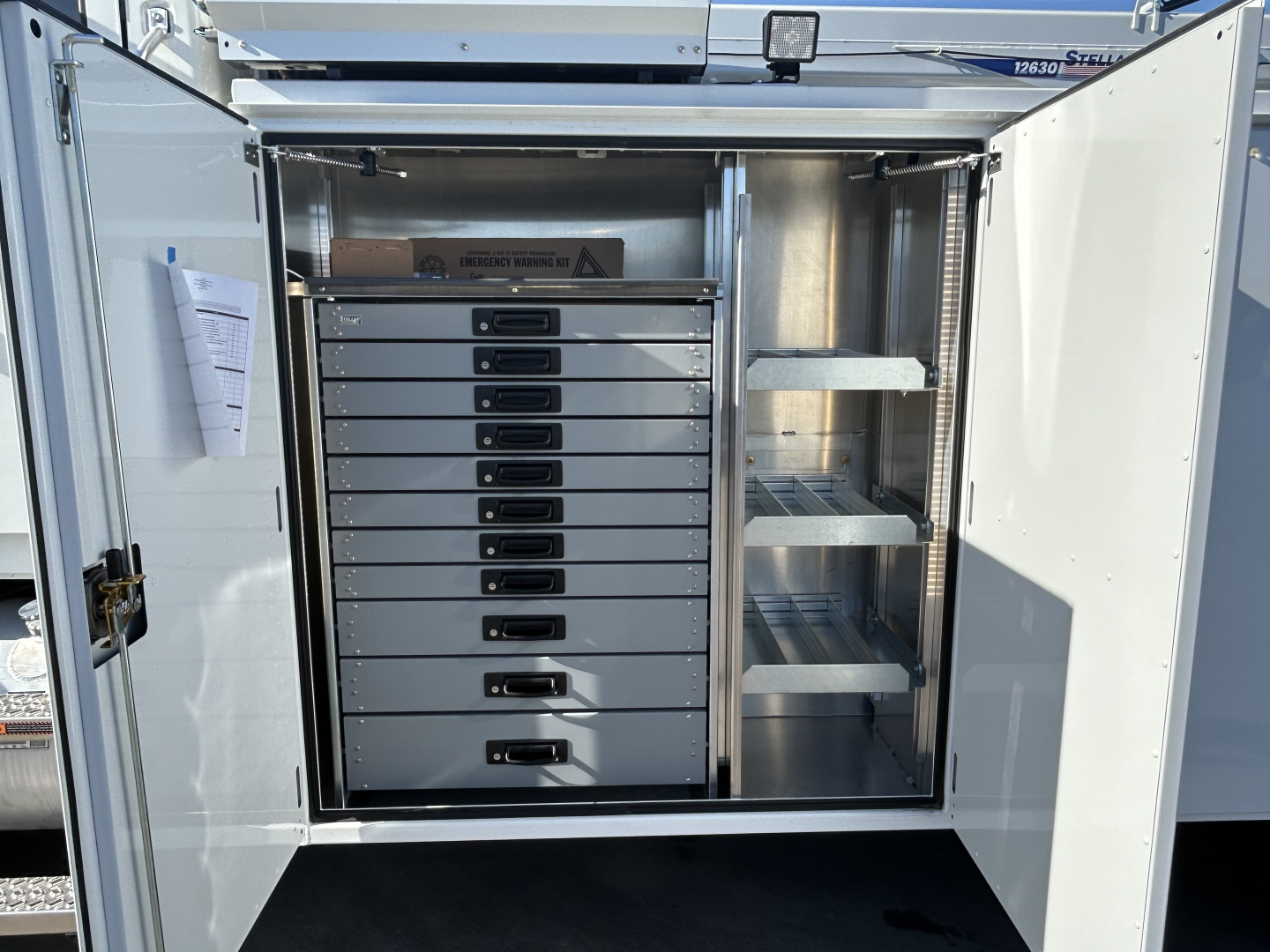 MD7 service truck rear with open storage compartments and tool drawers, showing multiple labeled drawers and shelves.