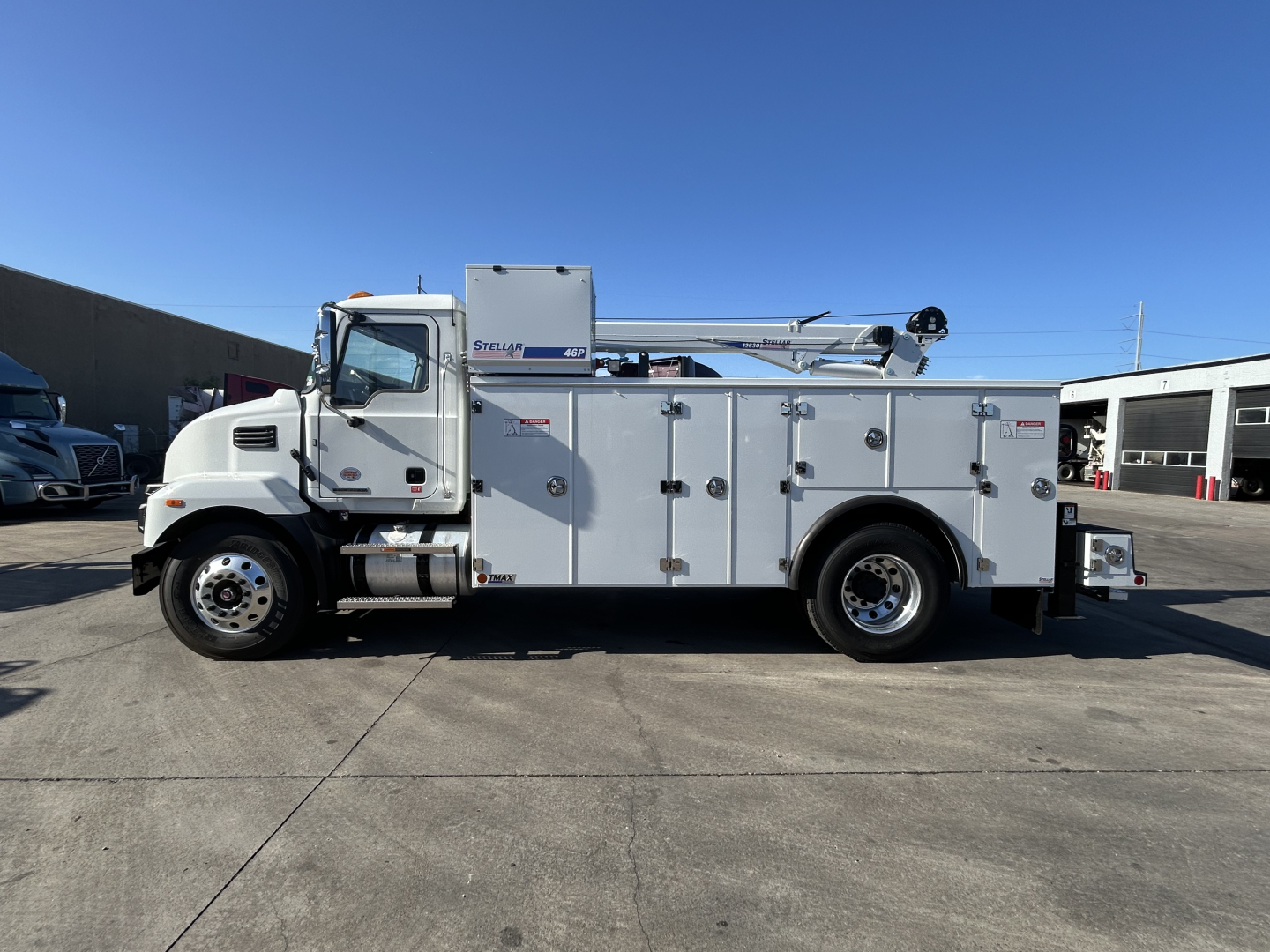 Service/utility truck side view showing multiple storage compartments, utility body, boom crane, and Mack MD7 cab.