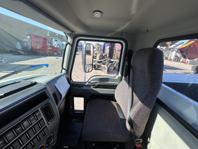 Cab interior of a 2025 Mack MD7 service truck showing driver seat and dashboard side window.