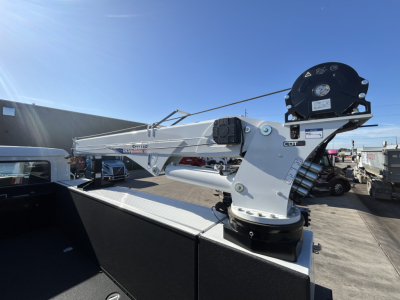 Truck-mounted knuckle-boom crane on a new 2025 Mack MD7 service truck. Visible are the crane arm with winch, hydraulic hoses, and rotating base.