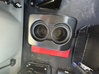 Service/Utility truck interior showing dual cupholders and a red label, with a black storage bin nearby.