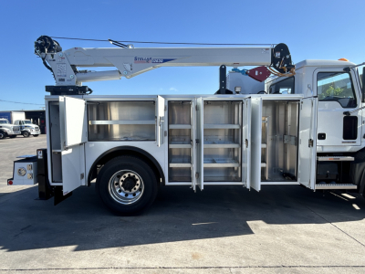 Truck body side with multiple compartments and a mounted crane on top of a white service utility truck.